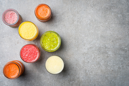 Glasses of fresh juice on gray stone table. Food backgroundの写真素材