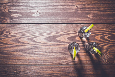 Shot glasses of vodka on wooden tableの写真素材