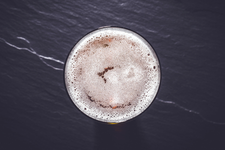 Beer glass on dark gray stone background. Top viewの写真素材