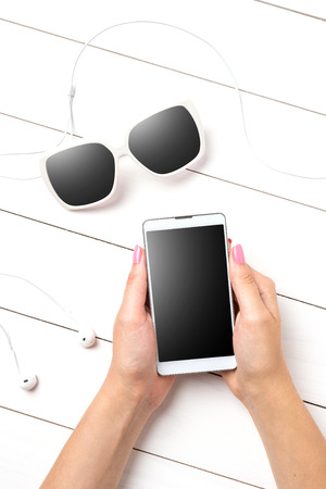 Woman using modern smart phone over white wooden tableの写真素材