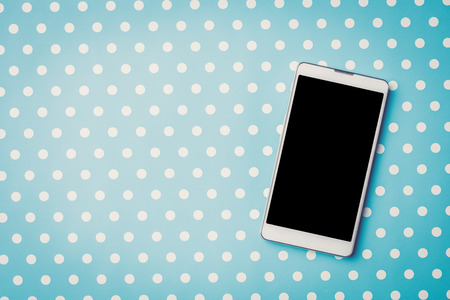 White mobile phone over blue dotted background