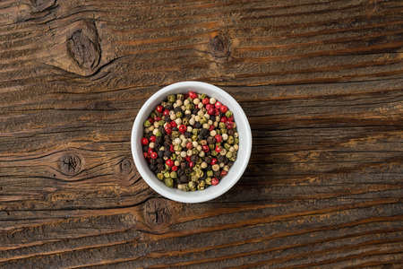 Colorful pepper in a bowl on an old wooden tableの写真素材