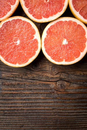 Red grapefruits on an old wooden tableの写真素材