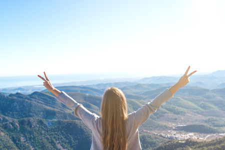 Beautiful women showing peace sign while enjoying mountains landscape
