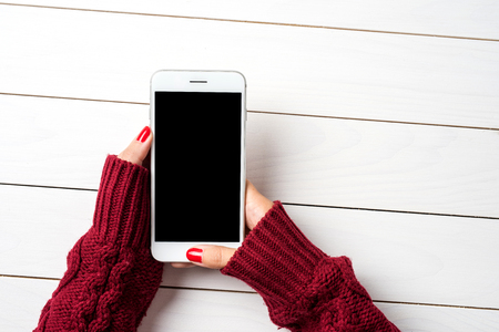 Woman using a smartphone in warm sweater. Close upの写真素材