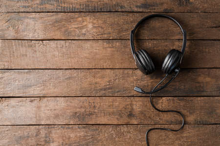 Helpdesk headset on wooden background. Call center. Top viewの写真素材