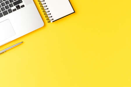 Elegant office desktop with laptop, notebook and pen on yellow background with copyspace. Modern...