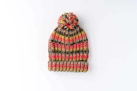 Multicolored winter woolen hat with pompom isolated on white background. Flat lay. Top view