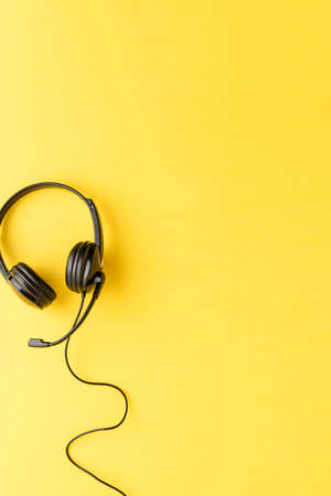 Call center concept. Helpdesk headset on yellow desktop with copyspaceの写真素材