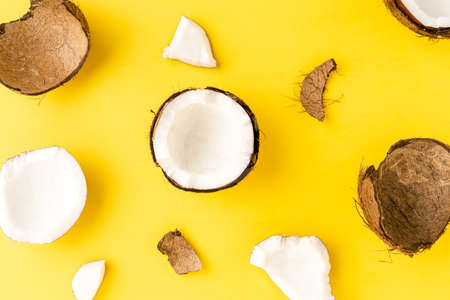 Overhead shot of fresh cracked coconut on yellow background. Flat layの写真素材
