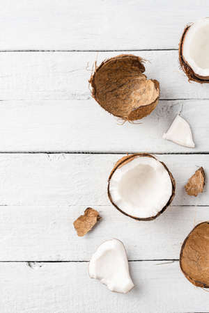 Fresh cracked coconut on white wooden background with copyspace. Flat lay