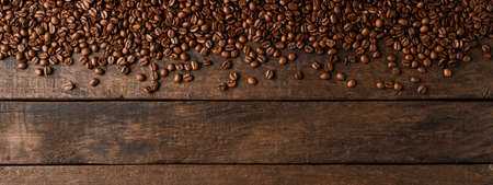 Coffee beans on wooden background with copyspace.