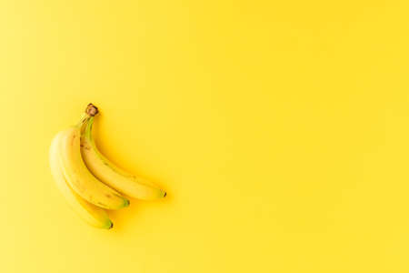 Bunch of fresh bananas on yellow background with copyspace. Top viewの写真素材