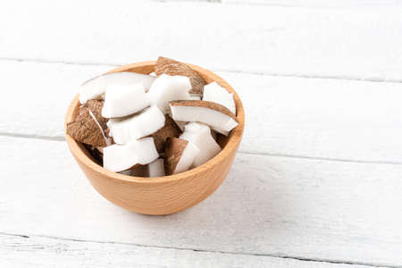 Fresh coconut pieces in bowl on white wooden backgroundの写真素材