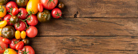 Various kinds of tomatoes on rustic wooden table with copyspace. Food background. Top view. Bannerの写真素材