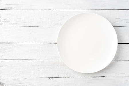 Empty white plate on wooden table. Top viewの写真素材