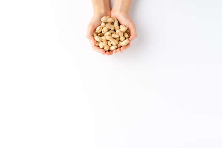 Female hands holding peanuts isolated on white background with copyspace. Top view