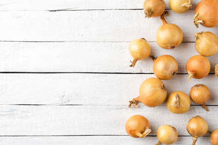 Overhead shot of onions on white wooden background with copyspace