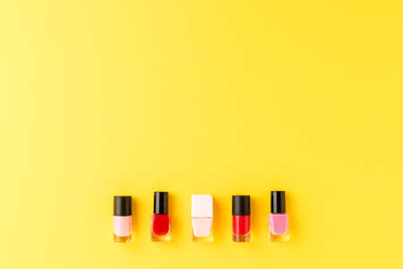 Red and pink nail polishes on yellow background with copyspace. Top viewの写真素材