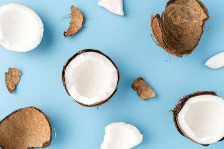 Overhead shot of fresh cracked coconut on blue background. Flat lay. Close up