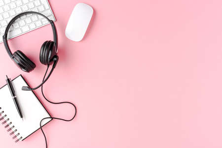 Call center desktop with headset and accessories on pink table. Top viewの写真素材