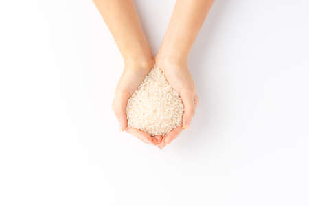 Overhead shot of woman's hands holding white rice grains isolated on white backgroundの写真素材
