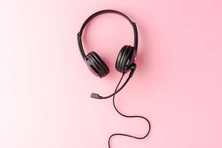 Call center concept. Helpdesk headset on pink desktop with copyspaceの写真素材