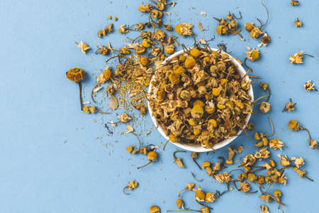 Dried chamomile flowers on blue background. Top viewの写真素材