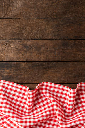 Red checkered tablecloth on wooden background with copyspace