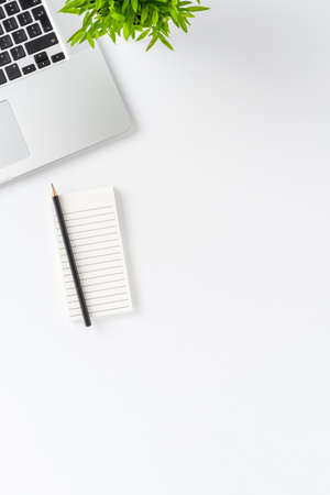 Laptop, notebook, pen and flower on white background with copyspace. Office desktop concept. Top viewの写真素材