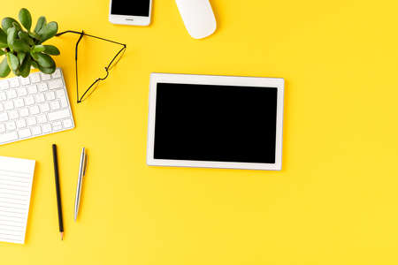 Digital tablet with empty screen on yellow background with business accessories. Office desktopの写真素材