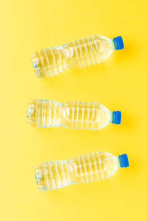 Plastic bottles with water on yellow table. Top viewの写真素材