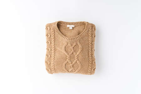 Beige folded sweater isolated on white background. Flat lay. Top view