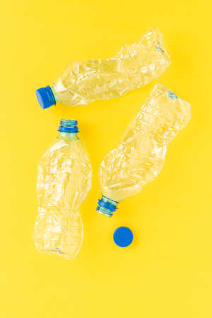 Used and crushed small bottles of water on yellow background. Plastic recycling. Top viewの写真素材