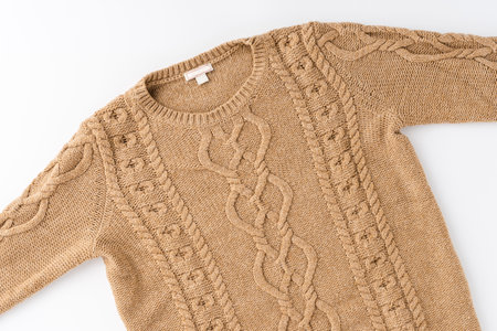 Beige knitted sweater isolated on white background. Flat lay. Top view