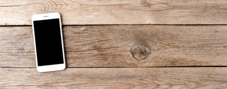 Smart phone with empty screen on wooden desk. Panoramic banner. Top viewの写真素材