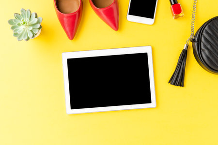 Digital tablet with empty screen on yellow background with female outfit. Fashion backgroundの写真素材