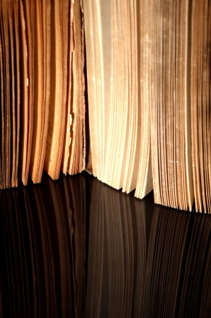 Open old book with vintage pages reflected in black surfaceの写真素材