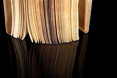 Open old book with vintage pages reflected in black surfaceの写真素材