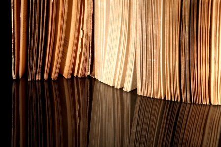 Open old book with vintage pages reflected in black surfaceの写真素材