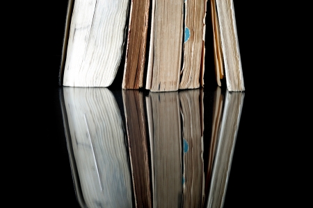 Pile of old books with vintage pages reflected in black surfaceの写真素材