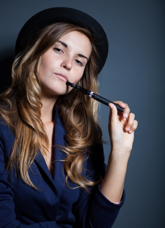 Elegant woman holding and smoking e-cigaretteの写真素材