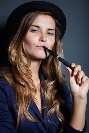 Elegant woman holding and smoking e-cigaretteの写真素材