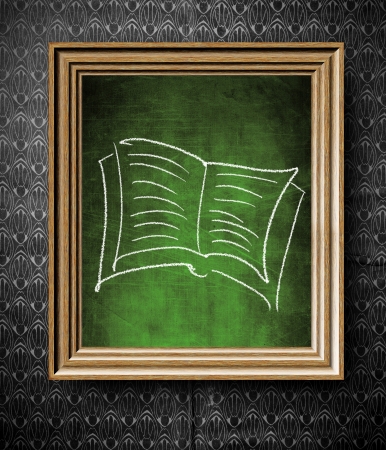 Book symbol chalkboard in old wooden frame on vintage wallの写真素材