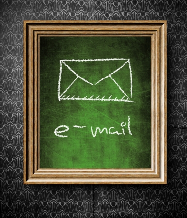 E-mail symbol chalkboard in old wooden frame on vintage wallの写真素材