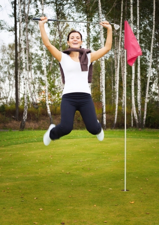 Overjoyed and smiling woman golf player in winner pose on greenの写真素材