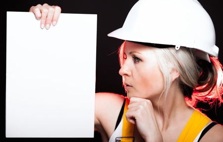 Young architect woman construction worker holding empty banner, glowing lightsの写真素材