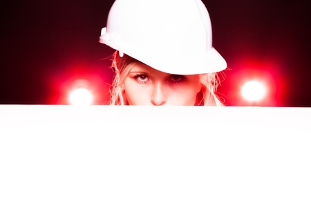 Young architect woman construction worker holding empty banner, glowing lightsの写真素材