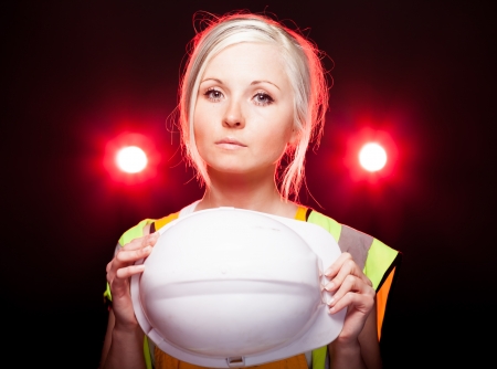 Young architect woman construction worker holding safety helmet, glowing lightsの写真素材