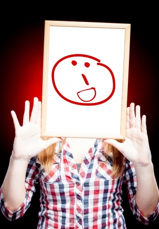 Woman showing a grin emoticon in front of faceの写真素材